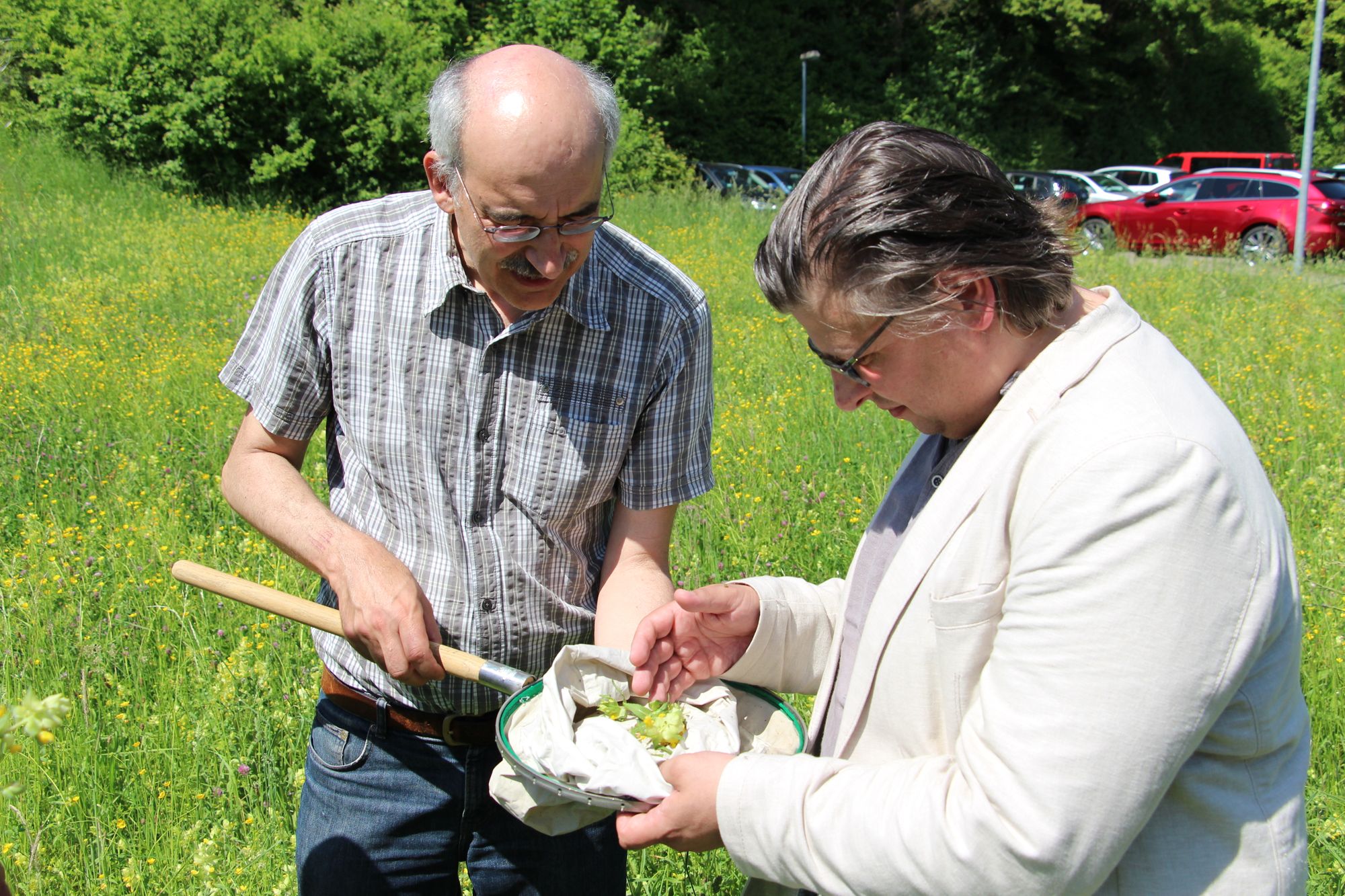 Professor Oliver Betz zeigt Daniel Lede Abal, die Blumen und Insekten, die er in einem Kescher auf der Wiese gefangen hat